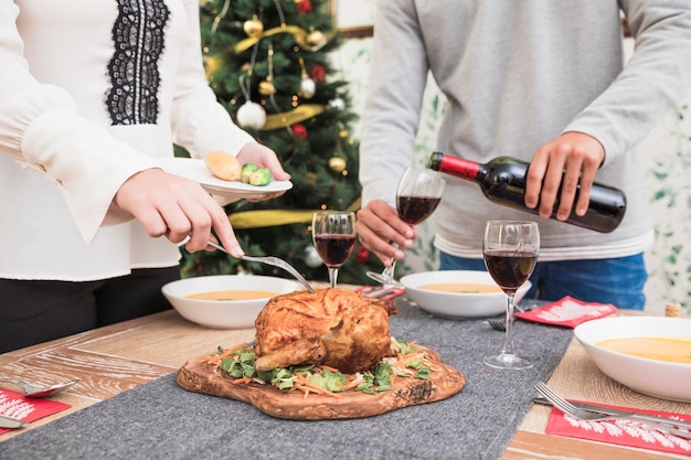 Mujer tomando pollo al horno de la mesa de Navidad