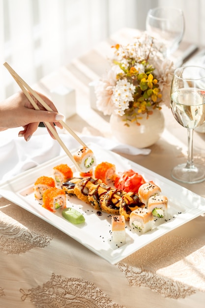 Mujer tomando rollos de sushi con palillos