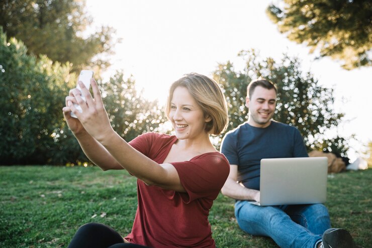 Foto gratuito mujer tomando selfie cerca de hombre con laptop