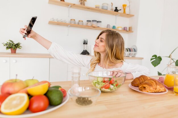 Mujer tomando selfie en cocina