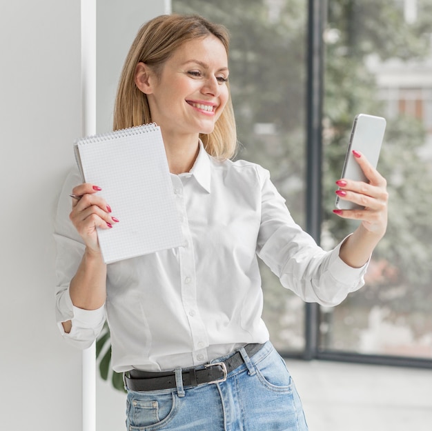 Mujer tomando una selfie con un cuaderno