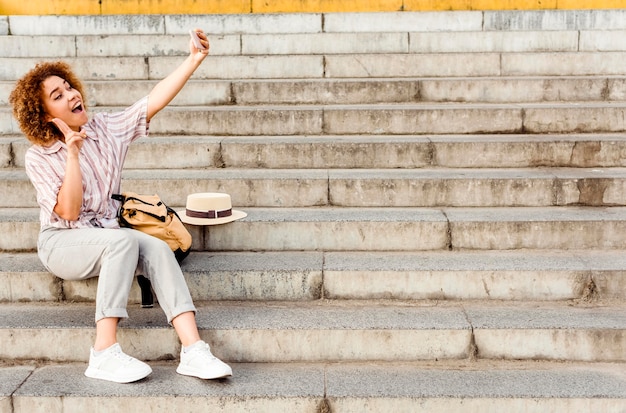 Mujer tomando un selfie en las escaleras con espacio de copia