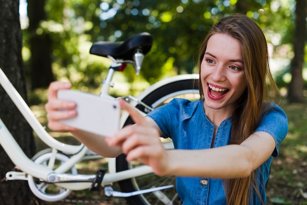 Mujer tomando selfie junto a la bicicleta