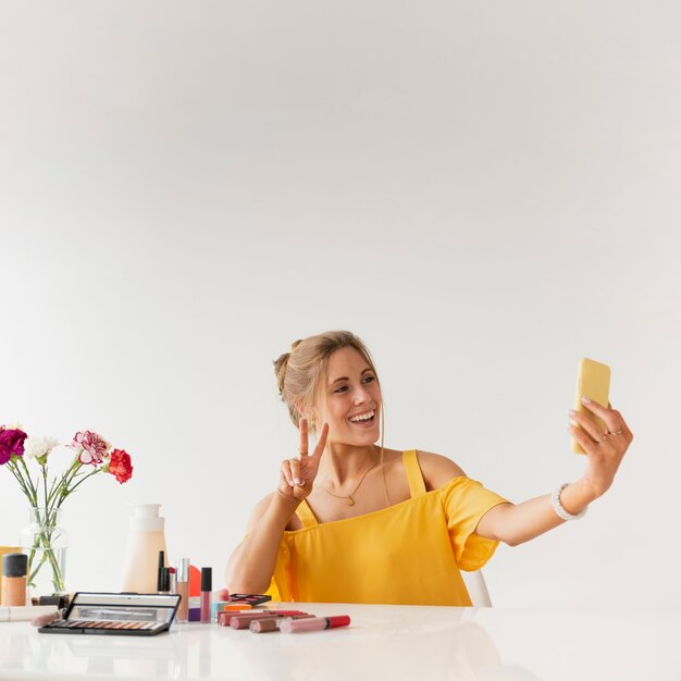 Mujer tomando selfie mientras muestra signo de paz