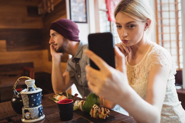 Mujer tomando selfie mientras que hombre hablando por teléfono