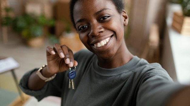 Mujer tomando selfie mientras sostiene las llaves de su nuevo hogar
