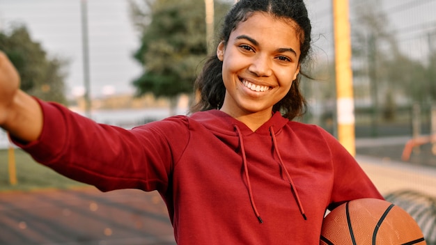 Foto gratuita mujer tomando un selfie con una pelota de baloncesto