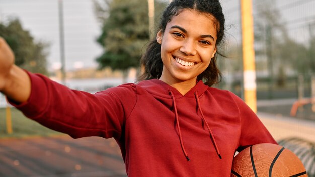 Mujer tomando un selfie con una pelota de baloncesto