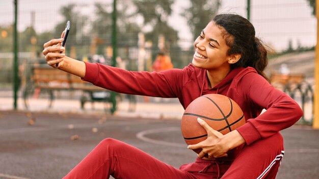 Mujer tomando un selfie con una pelota de baloncesto