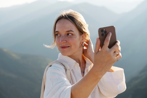 Mujer tomando selfie en tiro medio de montaña