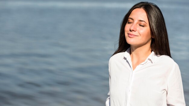 Mujer tomando el sol y la brisa de la playa con espacio de copia