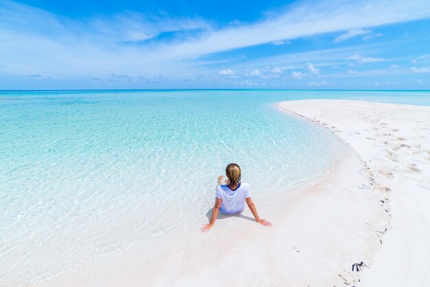 Mujer tomando el sol en la pintoresca playa de arena blanca, vista