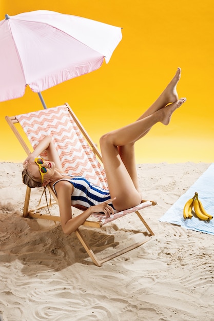 Mujer tomando el sol bajo una sombrilla en la hermosa playa y disfrutando el momento