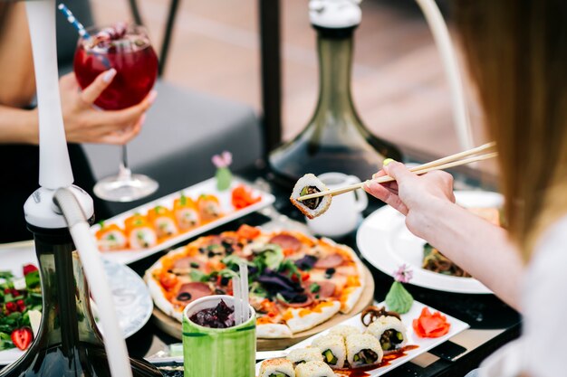 Mujer tomando sushi con palillos servidos para la cena