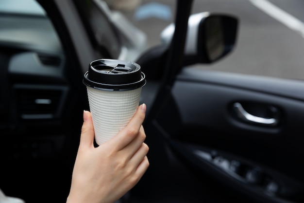 Mujer tomando una taza de café con su auto eléctrico