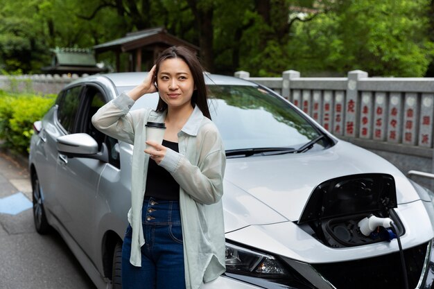 Mujer tomando una taza de café con su auto eléctrico