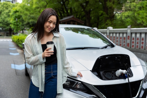 Mujer tomando una taza de café con su auto eléctrico