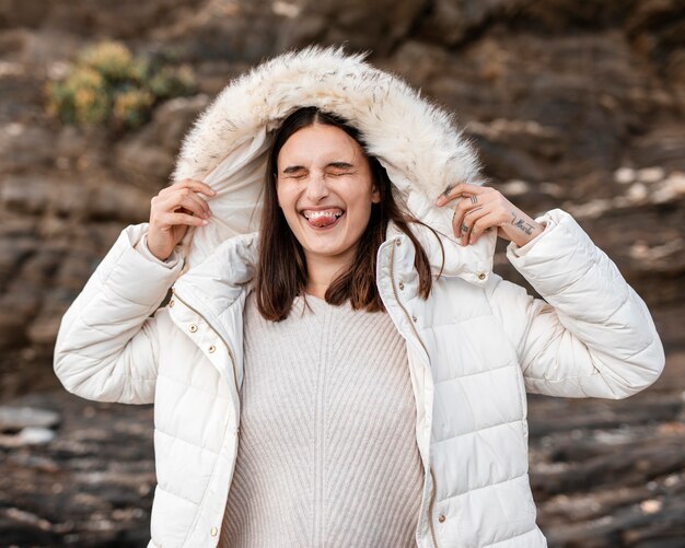 Mujer tonta en la playa con chaqueta de invierno