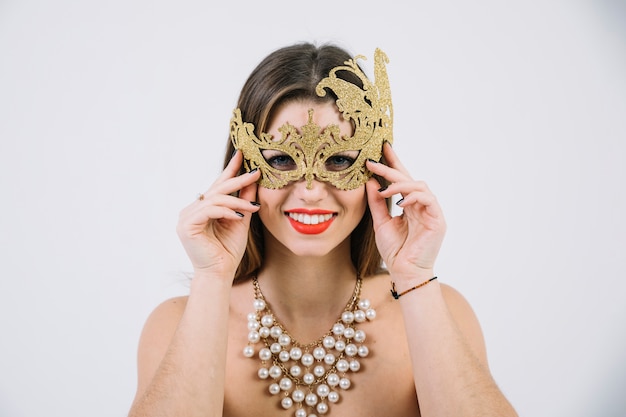 Mujer en topless sonriente con máscara de carnaval decorativa dorada y collar