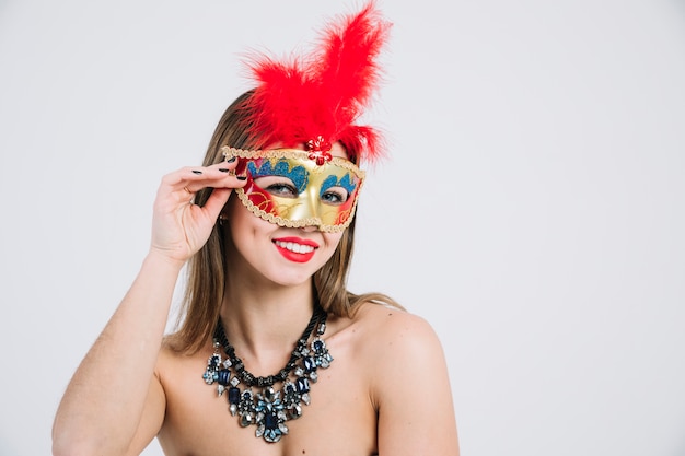 Mujer en topless sonriente con mascarada máscara de carnaval sobre fondo blanco