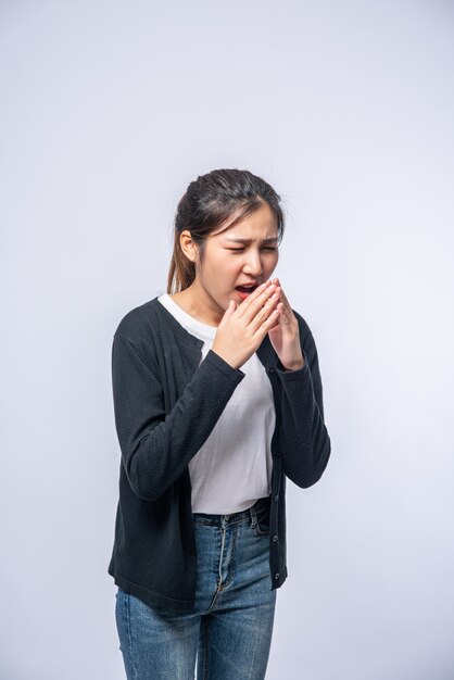 Una mujer tosiendo y tapándose la boca con la mano.