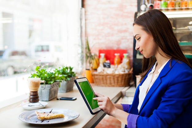 Mujer trabaja con una tableta en la mesa en un café