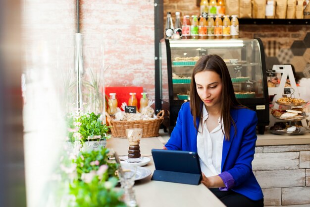 Mujer trabaja con una tableta en la mesa en un café