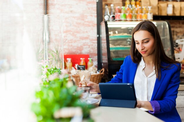 Mujer trabaja con una tableta en la mesa en un café