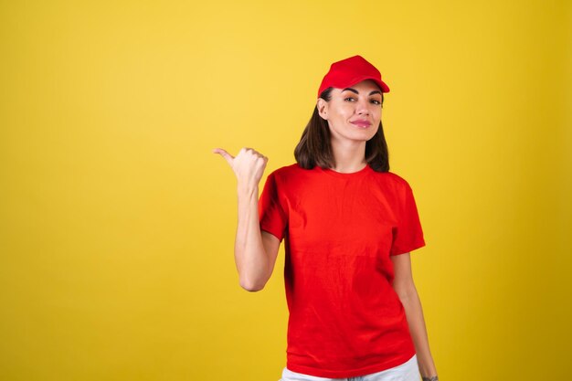 Mujer trabajadora de servicio de entrega en uniforme rojo señalar con el dedo a la izquierda