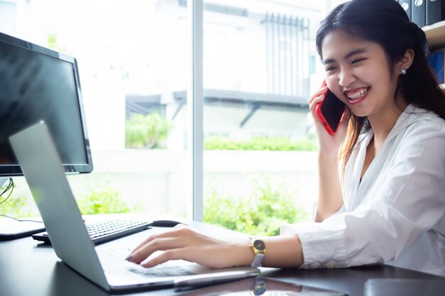 Mujer trabajadora sonriendo mientras habla con el teléfono inteligente