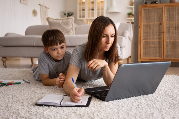 Mujer trabajando desde casa con niño tiro completo