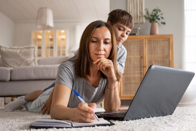 Mujer trabajando desde casa con niño tiro completo