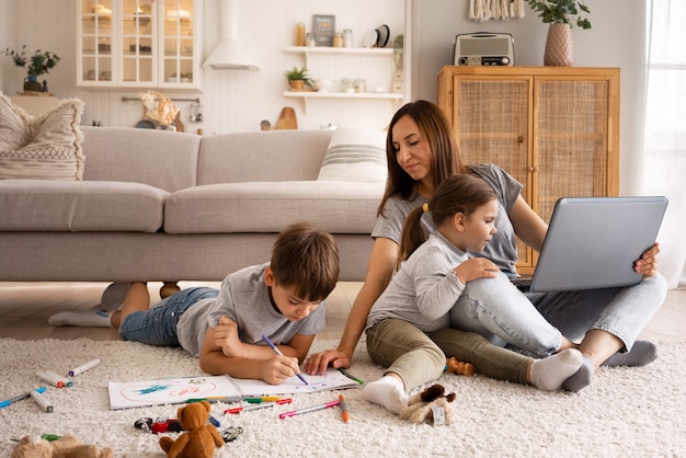 Mujer trabajando desde casa con niños tiro completo