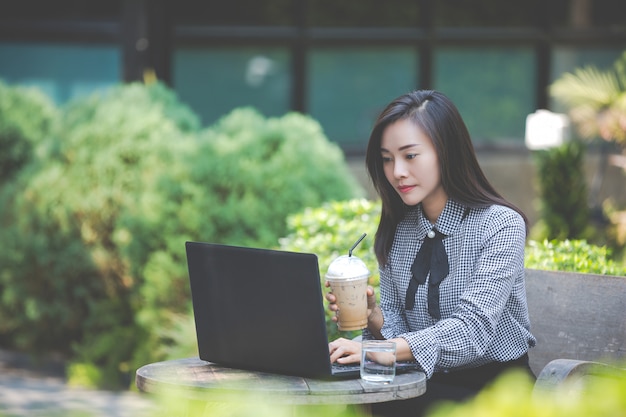 Mujer trabajando en la computadora portátil en la cafetería y tomando café