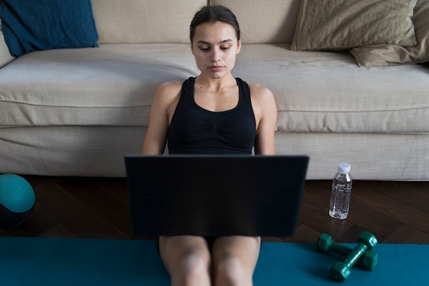 Foto gratuita mujer trabajando en una computadora portátil con pesas junto a ella