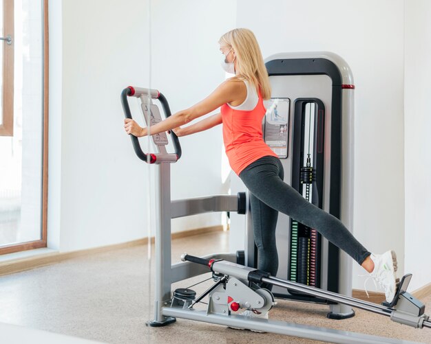 Mujer trabajando en el gimnasio con máscara médica