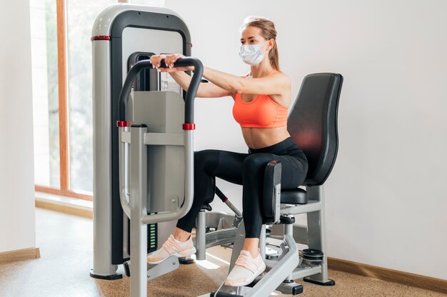 Mujer trabajando en el gimnasio con máscara