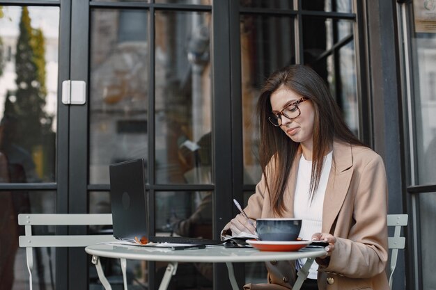 Mujer trabajando en un portátil en un café de la calle