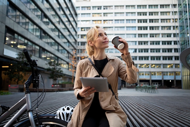 Mujer trabajando en su tableta afuera y tomando café