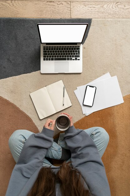 Mujer trabajando en el suelo desde casa con dispositivo