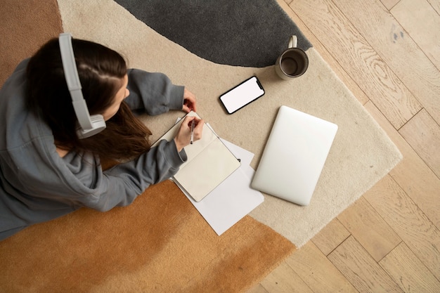 Mujer trabajando en el suelo desde casa con dispositivo