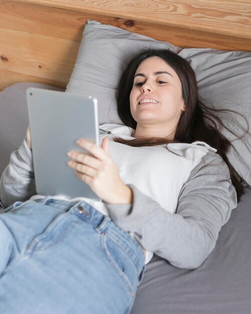 Mujer trabajando en tableta en la cama