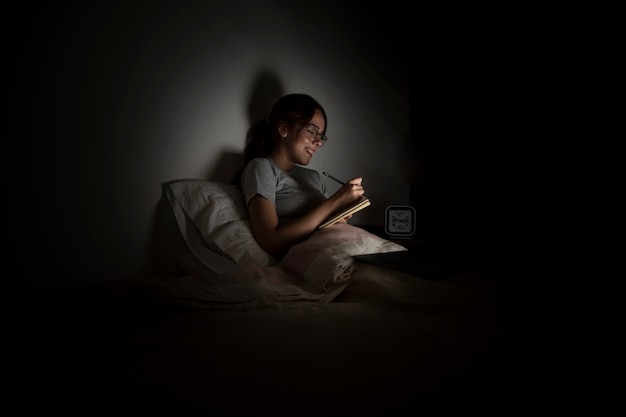 Mujer trabajando hasta tarde en casa mientras está en la cama