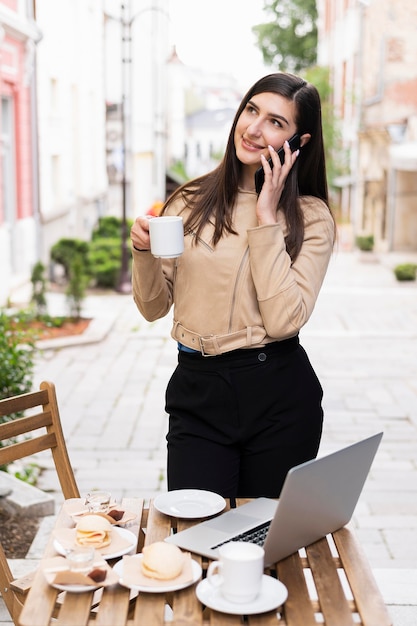 Mujer trabajando y tomando café al aire libre