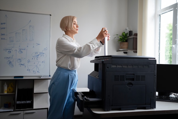 Mujer en el trabajo en la oficina usando impresora