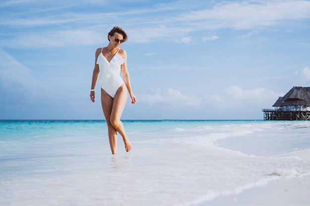 Mujer en traje de baño blanco junto al mar