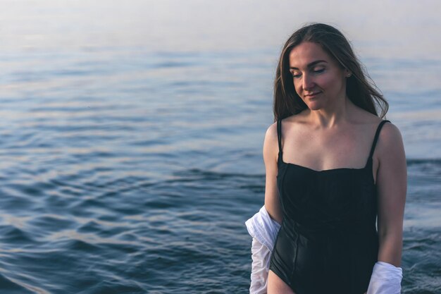 Una mujer en traje de baño y una camisa blanca en el mar.