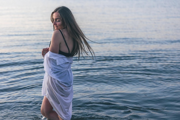 Una mujer en traje de baño y una camisa blanca en el mar.