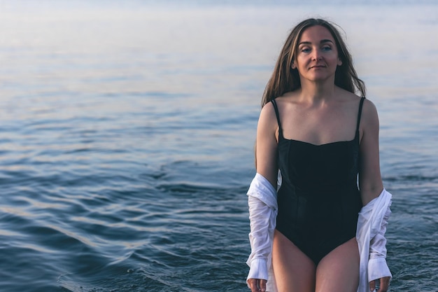 Una mujer en traje de baño y una camisa blanca en el mar.