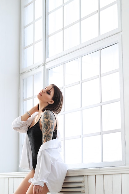 Mujer en traje de baño negro y camisa blanca.